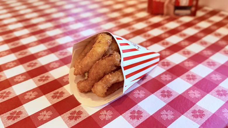 Cup of onion rings on checkered tablecloth