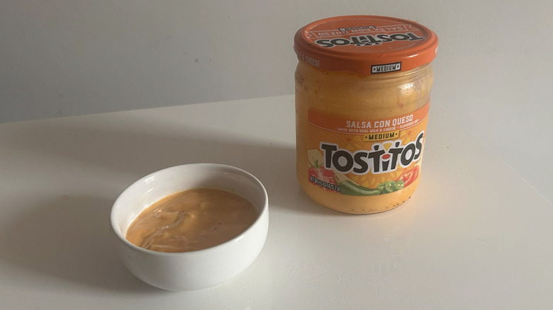 A jar of Tostitos queso sitting next to a little bowl