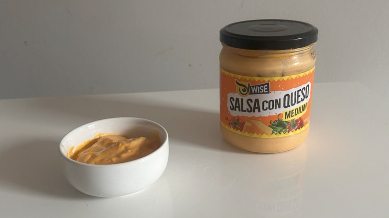A jar of Wise salsa con queso next to a small bowl