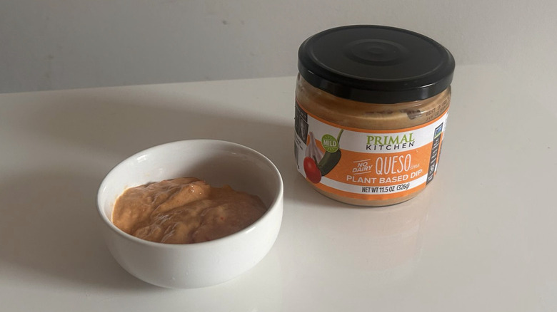 A jar of Primal Kitchen queso with some spooned out into a little white bowl