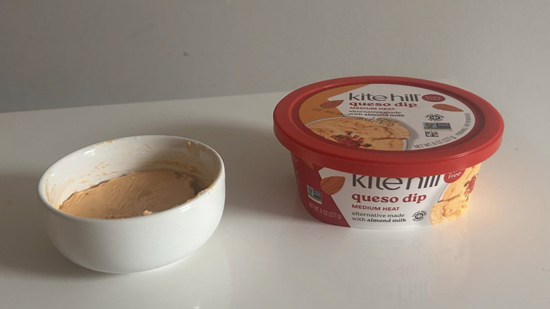 A tub of Kite Hill queso dip spooned into a little bowl
