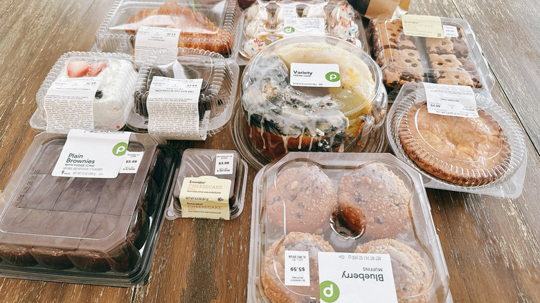 Variety of Publix bakery items on a wooden table in plastic packaging, including brownies, blueberry muffins, and creme cake