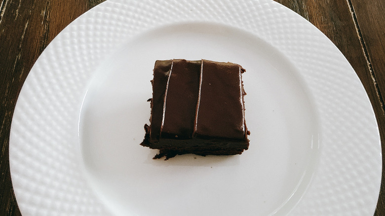 Publix brownie with fudge icing on white plate on wooden table