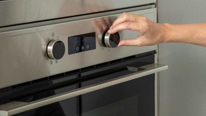 Hand of a person using the temperature selector of an oven