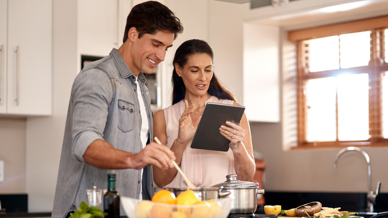 Couple cooking and using a tablet for the recipe
