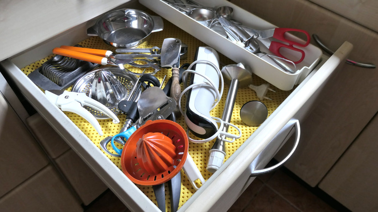 The inside of a kitchen utensil drawer showing measuring spoons, baking equipment, and other kitchen utensils