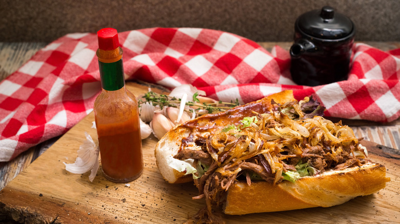 a roast beef po-boy with a bottle of hot sauce
