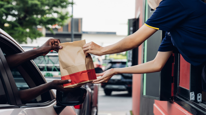 A driver being handed a drive-thru order from a fast food restaurant.
