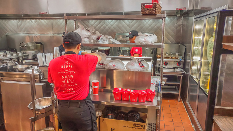 A Panda Express kitchen with employees preparing takeout orders