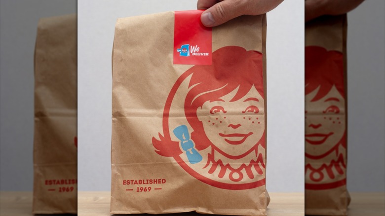 A Wendy's takeout bag with a hand picking it up