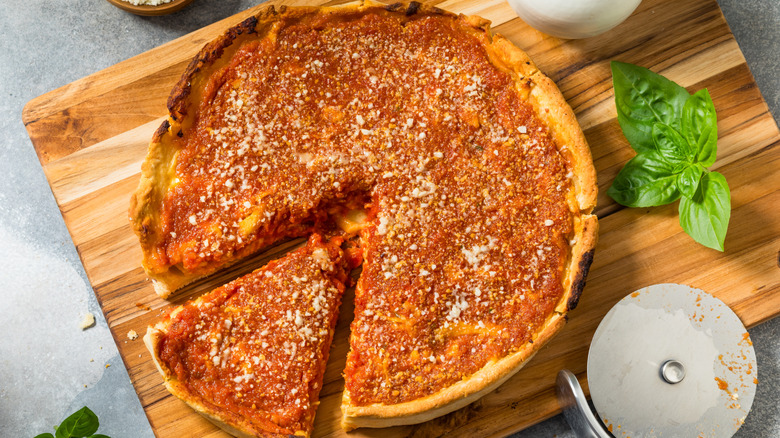 A Chicago deep dish pizza cut on a wooden board