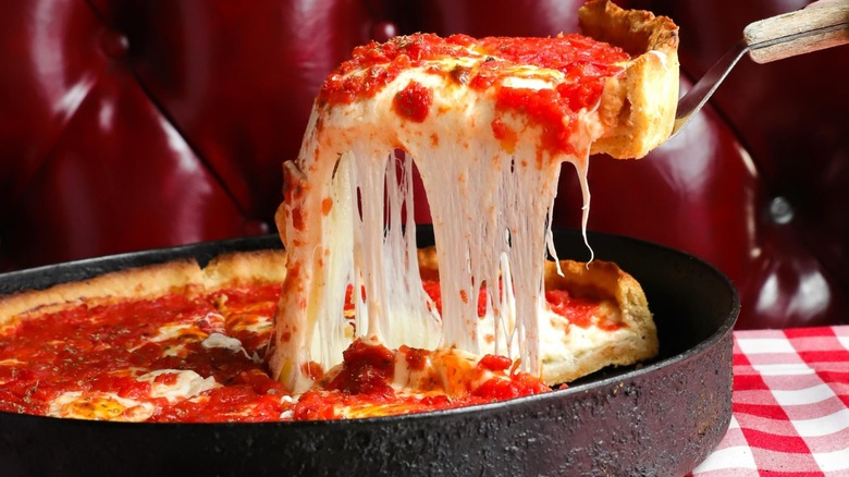 A slice of cheesy Pizano's deep dish pizza being lifted from the pan