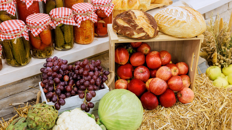 Baskets of apples, grapes, and vegetables alongside loaves of bread at a farmer's market