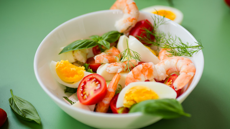 Vegetable salad with seafood and eggs in a white bowl