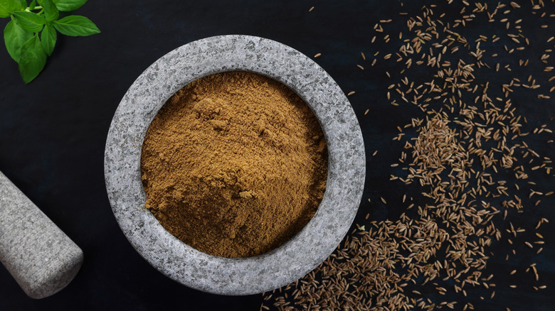 A mortar and pestle, cumin, and seeds