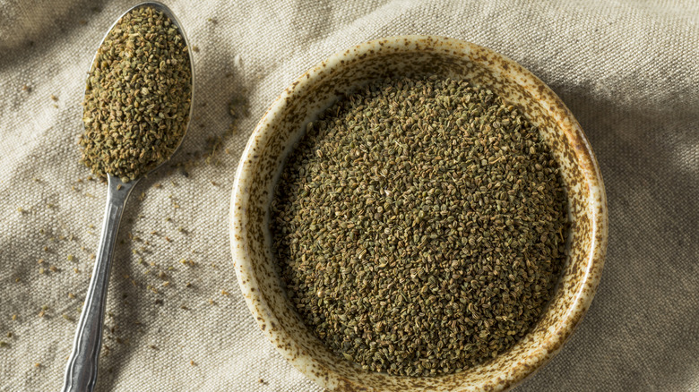 Celery seeds in a ceramic bowl and a metal spoon