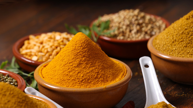 Ground cumin in a small earthenware bowl, surrounded by other spices in similar bowls