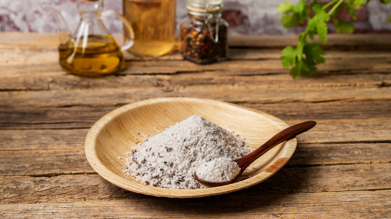 Truffle salt in a small wooden bowl with a small wooden spoon inserted into the bowl