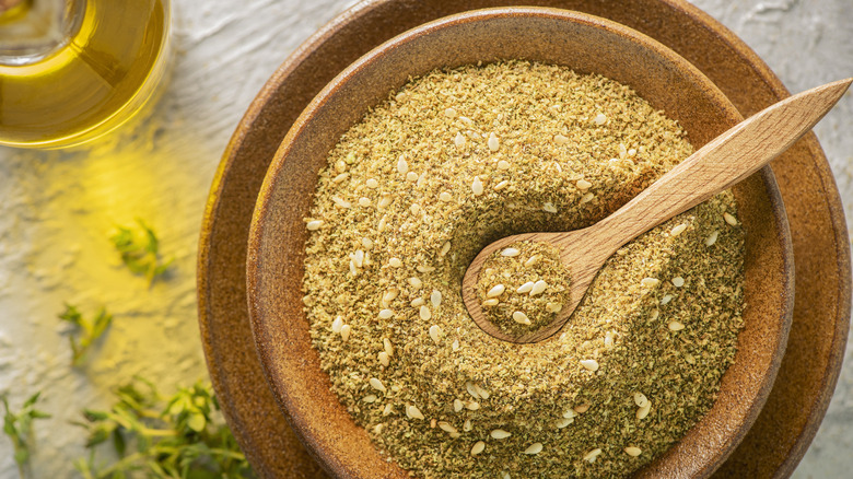 Za'atar spice blend in a brown bowl with a wooden spoon scooping out of it