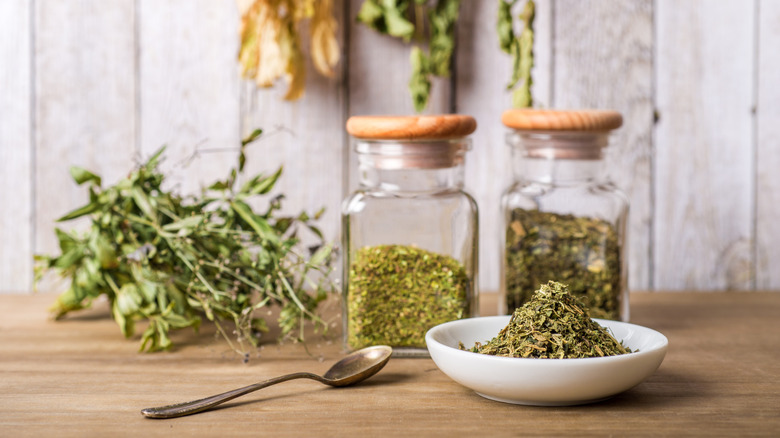 Dried herbs in glass jars and a dish with a spoon