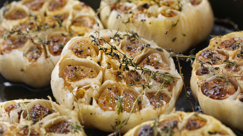 Roasted half garlic bulbs with seasonings in a skillet