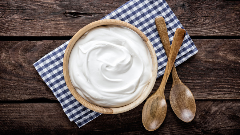 Sour cream in a wooden bowl with two spoons