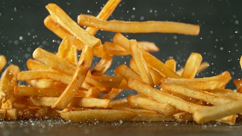A pile of french fries falling onto the table.