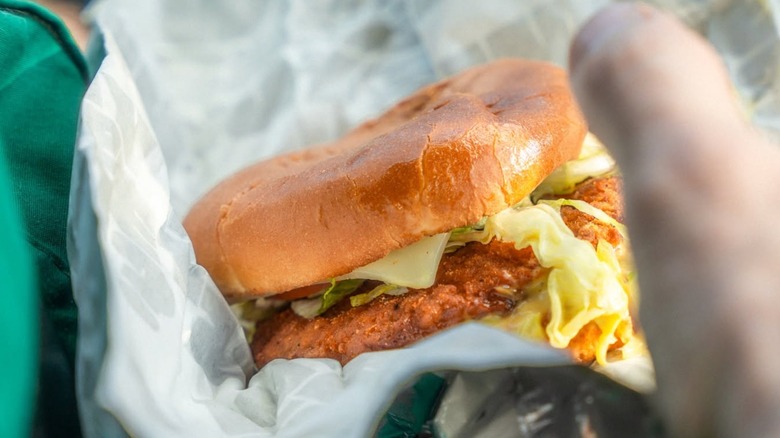 A hand holding a Sheetz chicken sandwich in a wrapper