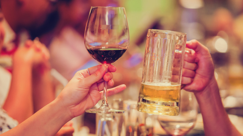 Restaurant diners holds up a wine glass and a mug of beer.