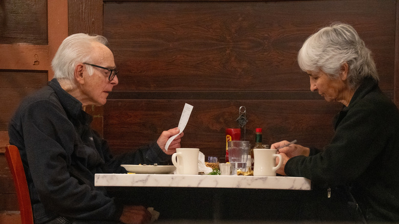 A photo of a retired couple getting the bill in a restaurant.