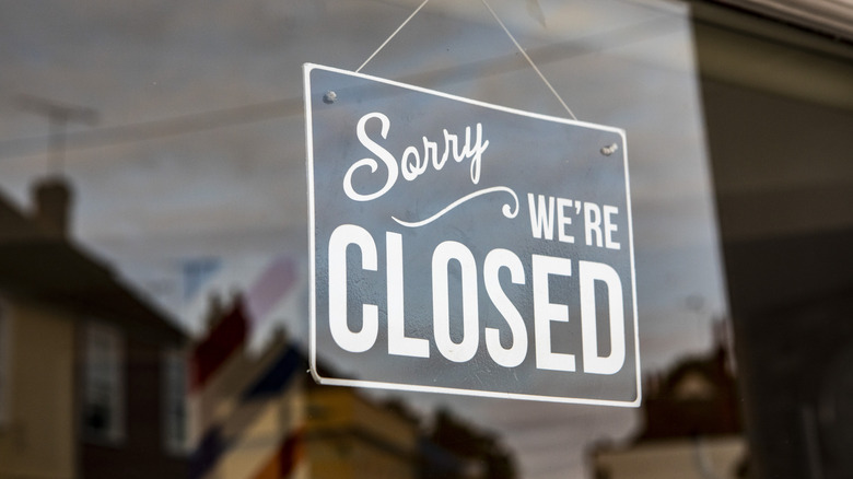 A "sorry, we're closed" sign hanging in a restaurant window.