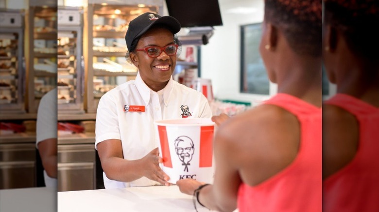 A KFC employee handing chicken to a customer