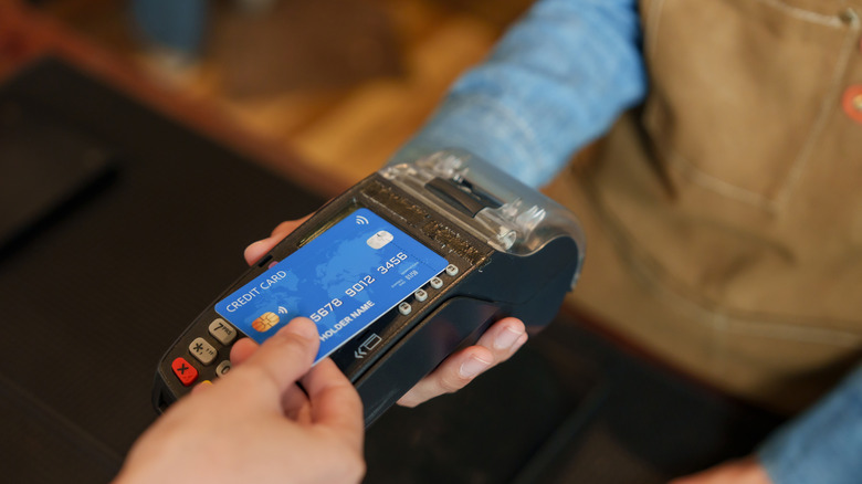 Close-up of a customer tapping a credit card to pay at a bakery