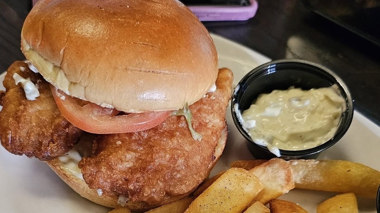 Red Robin's Crispy Fish sandwich with fries and tartar sauce on side.