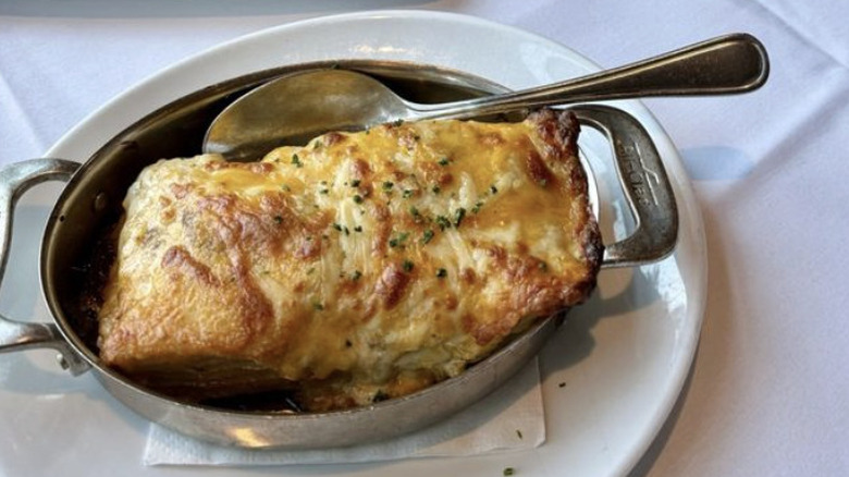 Fleming's Steakhouse signature potatoes in silver serving bowl, with spoon and white plate underneath