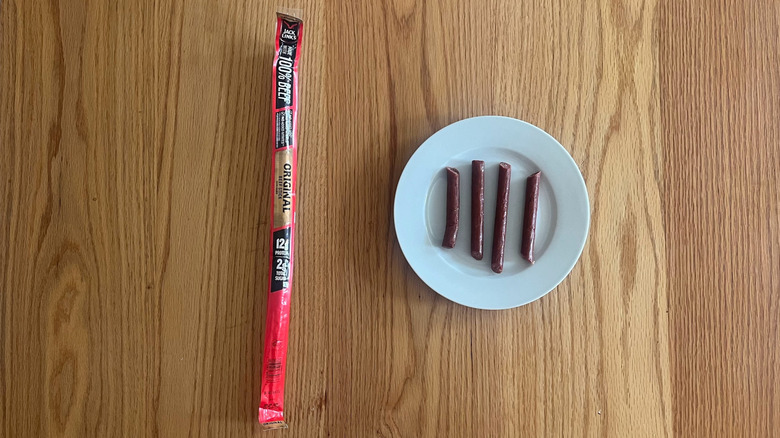 A Jack Links meat stick wrapper next to a plate with a Jack Links meat stick cut up on a plate