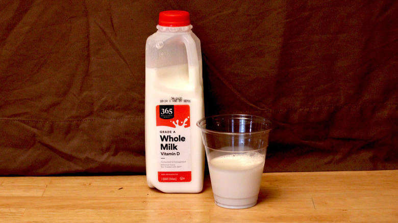 A jug of Whole Foods' 365 brand whole milk beside a cup of milk