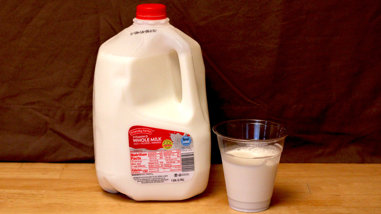 A jug of Aldi's Friendly Farms brand whole milk beside a cup of milk