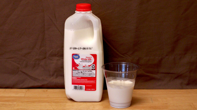 A jug of Walmart's Great Value brand whole milk beside a cup of milk