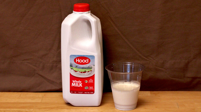 A jug of Hood brand whole milk beside a cup of milk