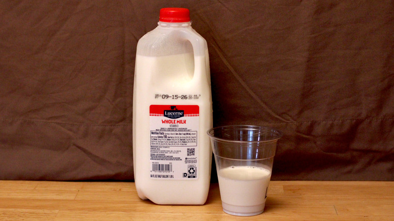 A jug of Lucerne brand whole milk beside a cup of milk