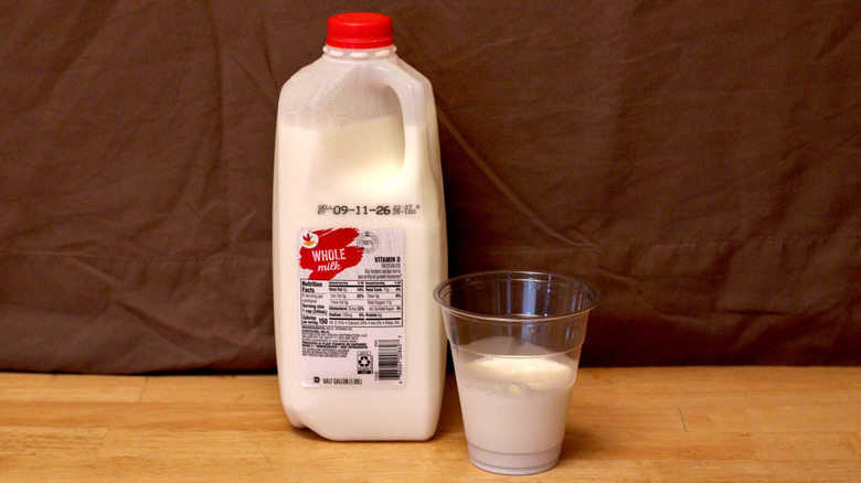 A jug of Stop & Shop brand whole milk beside a cup of milk