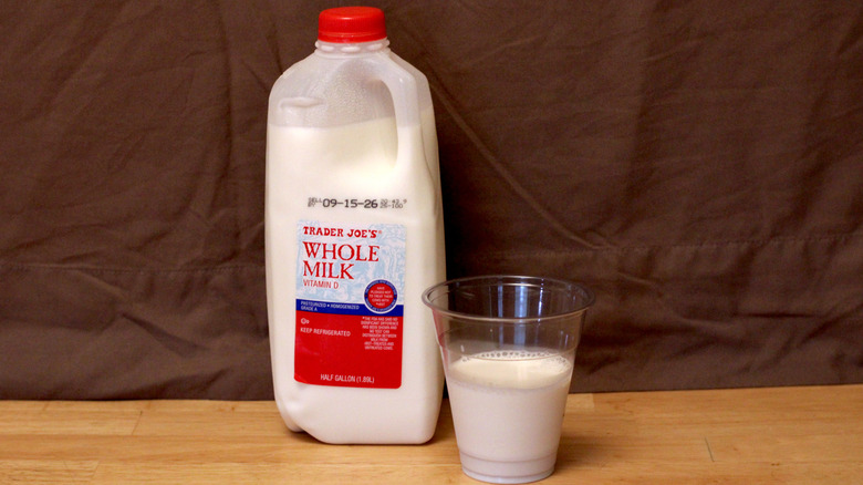 A jug of Trader Joe's brand whole milk beside a cup of milk