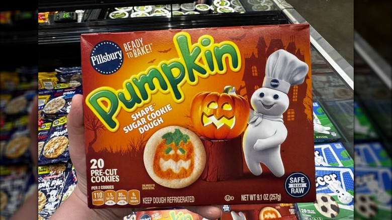 Someone holding a box of Pillsbury Pumpkin Shape Cookies in a grocery store