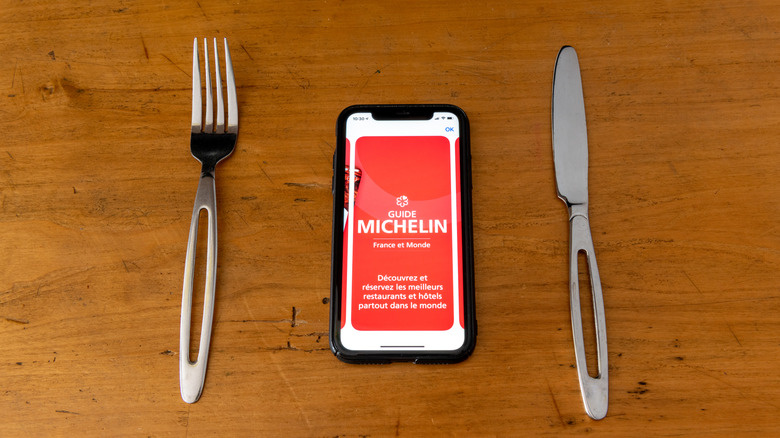 Red Michelin guide book on smartphone app with a knife and fork