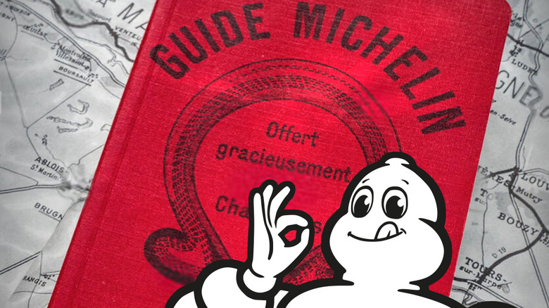 A close up of a red Michelin guide book with the Michelin man logo in front against a backdrop of a map