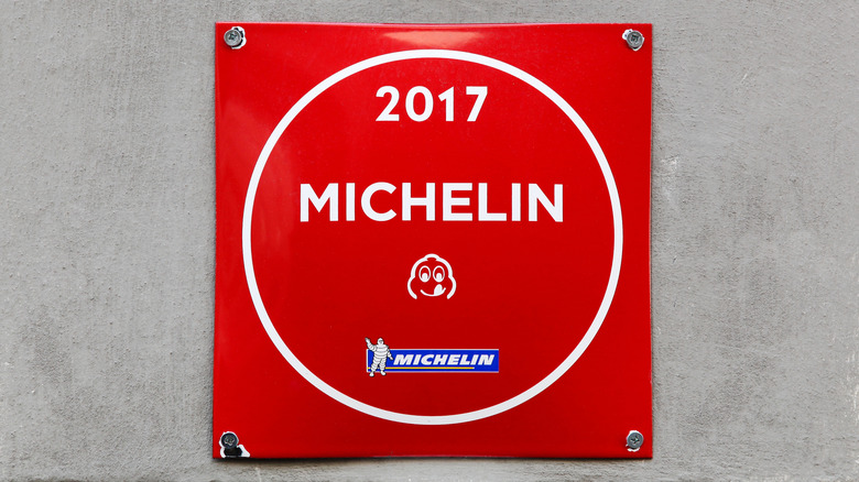 A red 2017 Michelin Guide Bib Gourmand sign on a restaurant wall