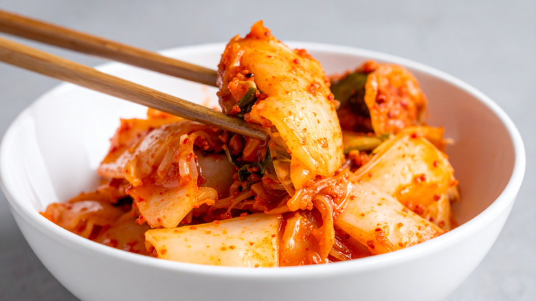 Kimchi in  a white bowl with chopsticks