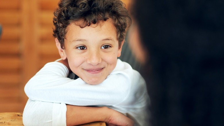 Young boy looking with his elbows resting on the table