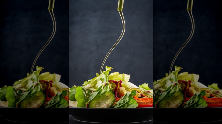 Olive oil being drizzled on a salad, mirrored
